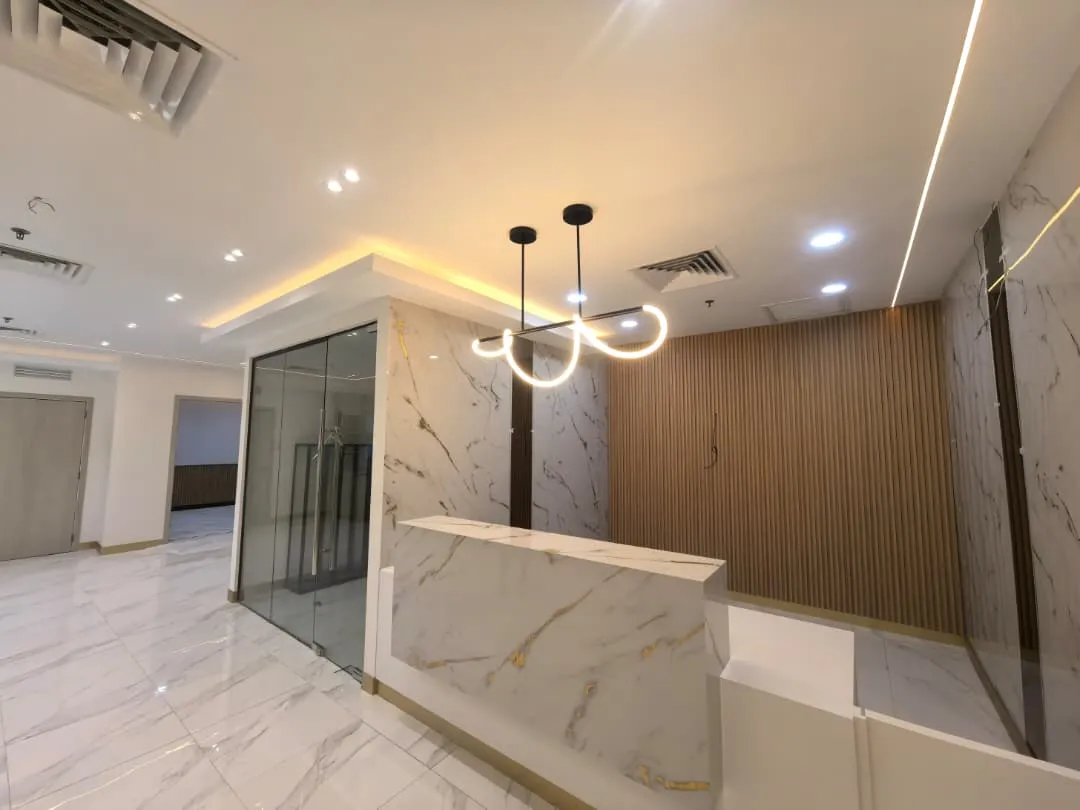 Modern office reception area with marble desk and stylish lighting.